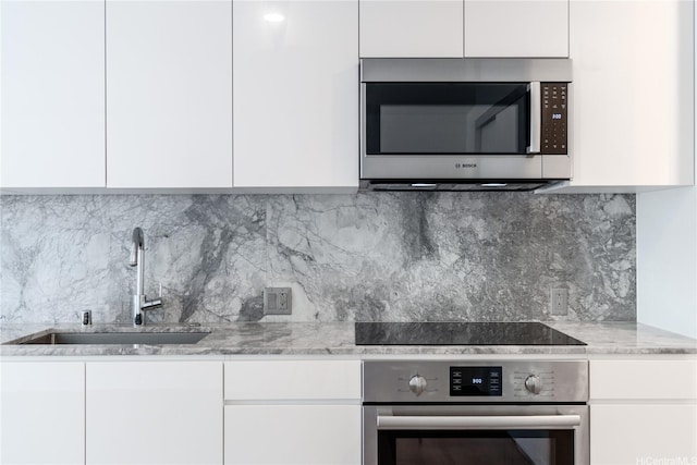 987 Queen St Unit 2308, Honolulu, HI 96814 - kitchen with appliances with stainless steel finishes, modern cabinets, white cabinetry, light stone counters, and tasteful backsplash