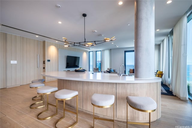 987 Queen St Unit 2308, Honolulu, HI 96814 - kitchen featuring decorative columns, open floor plan, light countertops, a kitchen bar, and light wood-style floors