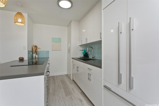 320 Liliuokalani Ave Unit 602, Honolulu, HI 96815 - kitchen with light wood-style flooring, paneled built in fridge, dark countertops, white cabinets, and black electric cooktop