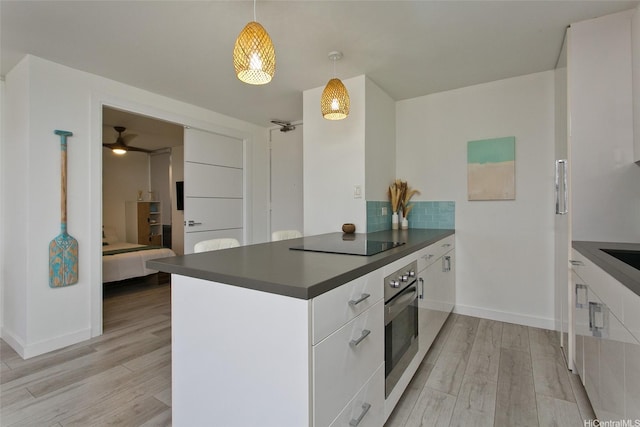 320 Liliuokalani Ave Unit 602, Honolulu, HI 96815 - kitchen featuring dark countertops, stainless steel oven, black electric cooktop, and white cabinetry