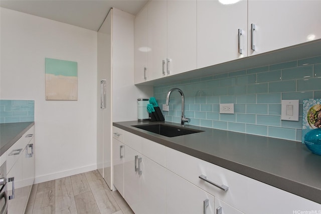 320 Liliuokalani Ave Unit 602, Honolulu, HI 96815 - kitchen featuring white cabinetry, decorative backsplash, dark countertops, and light wood-type flooring