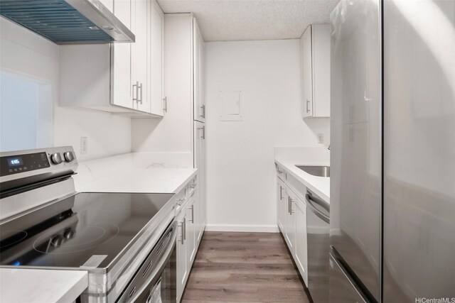 1215 Alexander St Unit 204, Honolulu, HI 96826 - kitchen featuring appliances with stainless steel finishes, extractor fan, light wood-style flooring, white cabinets, and a textured ceiling