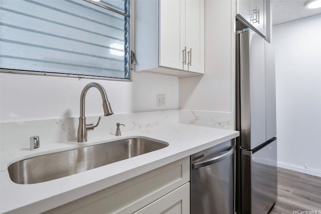 1215 Alexander St Unit 204, Honolulu, HI 96826 - kitchen featuring stainless steel appliances, white cabinets, light wood finished floors, light stone counters, and a textured ceiling