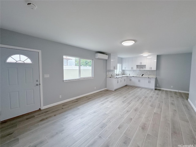811 20th Ave, Honolulu, HI 96816 - kitchen with a wall mounted AC, light countertops, white cabinetry, light wood-style flooring, and backsplash