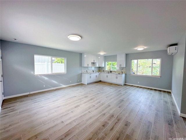 813 20th Ave, Honolulu, HI 96816 - unfurnished living room with an AC wall unit, light wood-style flooring, and healthy amount of natural light