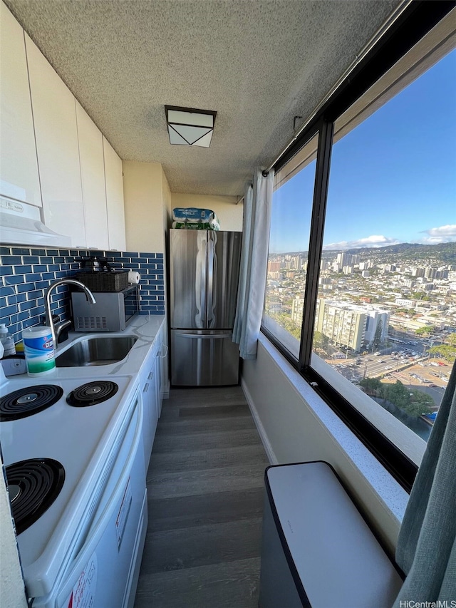 444 Niu St Unit 2906, Honolulu, HI 96815 - kitchen with freestanding refrigerator, under cabinet range hood, white cabinets, backsplash, and dark wood-type flooring