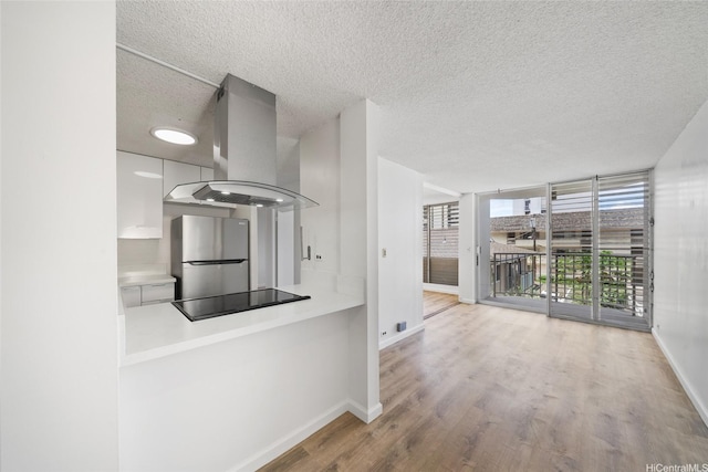 1535 Pensacola St Unit 208, Honolulu, HI 96822 - kitchen featuring island range hood, freestanding refrigerator, black electric cooktop, a textured ceiling, and white cabinetry