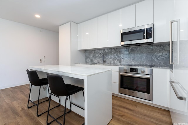 987 Queen St Unit 1512, Honolulu, HI 96814 - kitchen with stainless steel appliances, a center island, a breakfast bar, wood finished floors, and recessed lighting