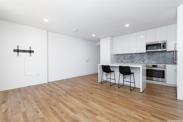 987 Queen St Unit 1512, Honolulu, HI 96814 - kitchen with stainless steel appliances, a breakfast bar, light countertops, white cabinetry, and decorative backsplash