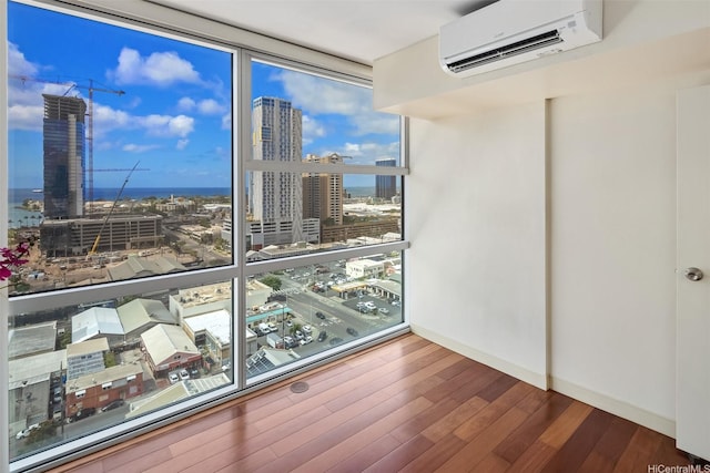 909 Kapiolani Blvd Unit 2002, Honolulu, HI 96814 - empty room with a wall mounted AC, a city view, a wall of windows, and wood finished floors