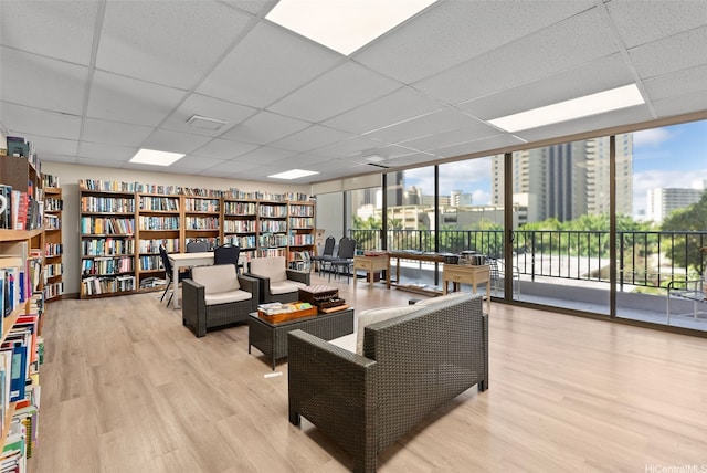 411 Hobron Ln Unit 3801, Honolulu, HI 96815 - living area featuring a paneled ceiling, wood finished floors, floor to ceiling windows, wall of books, and plenty of natural light