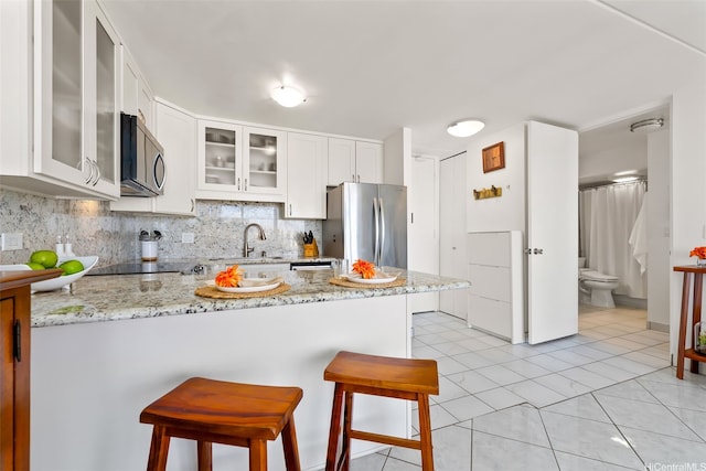 411 Hobron Ln Unit 3801, Honolulu, HI 96815 - kitchen featuring appliances with stainless steel finishes, a peninsula, a breakfast bar, tasteful backsplash, and glass insert cabinets