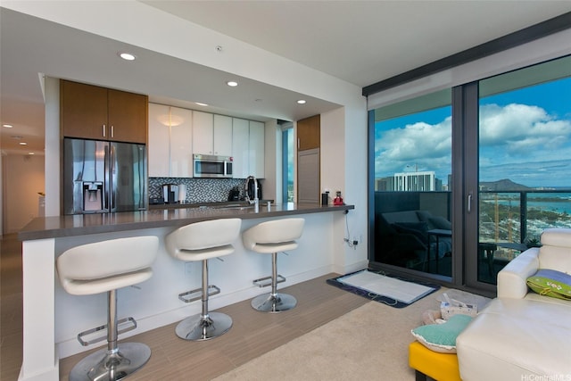 600 Ala Moana Blvd Unit 3401, Honolulu, HI 96813 - kitchen with refrigerator with ice dispenser, stainless steel microwave, dark countertops, tasteful backsplash, and wood finished floors