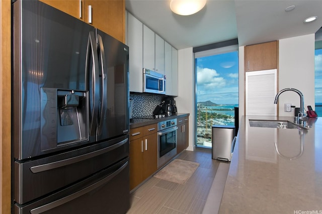 600 Ala Moana Blvd Unit 3401, Honolulu, HI 96813 - kitchen featuring stainless steel appliances, a wall of windows, backsplash, brown cabinets, and recessed lighting