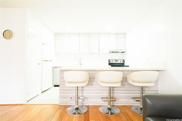 827 Kinau St Unit D703, Honolulu, HI 96813 - kitchen featuring range with electric cooktop, freestanding refrigerator, white cabinets, light countertops, and light wood-style floors