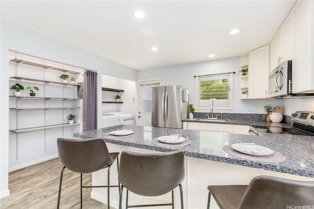 47-366 Hui Iwa St Unit 71, Kaneohe, HI 96744 - kitchen with open shelves, stainless steel appliances, washing machine and clothes dryer, a kitchen breakfast bar, and dark stone countertops