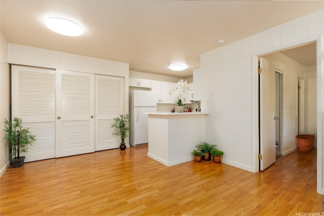 239 Mananai Pl Unit 54F, Honolulu, HI 96818 - kitchen with freestanding refrigerator, a peninsula, light countertops, white cabinetry, and light wood-type flooring