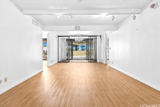 1600 Ala Moana Blvd Unit 306, Honolulu, HI 96815 - unfurnished living room with rail lighting, a chandelier, wood finished floors, and a textured ceiling