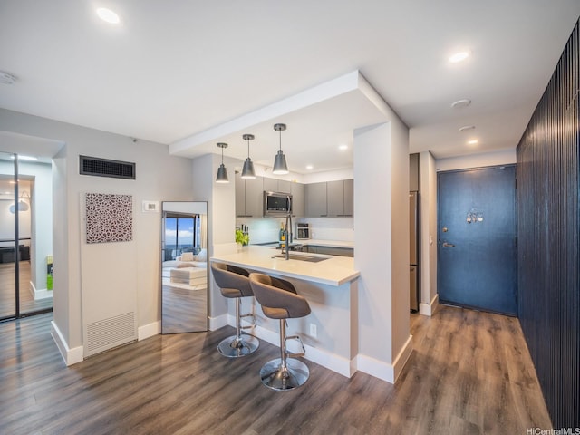 415 S St Unit 1602, Honolulu, HI 96813 - kitchen featuring stainless steel microwave, a breakfast bar, light countertops, dark wood-style flooring, and gray cabinets