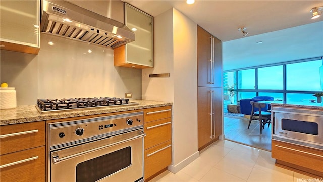 1177 Queen St Unit 1805, Honolulu, HI 96814 - kitchen with appliances with stainless steel finishes, extractor fan, light stone countertops, glass insert cabinets, and brown cabinets