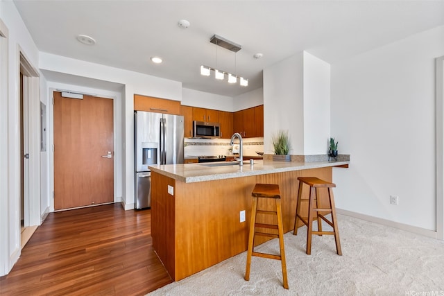 555 S St Unit 2303, Honolulu, HI 96813 - kitchen with appliances with stainless steel finishes, a peninsula, brown cabinetry, light countertops, and decorative backsplash