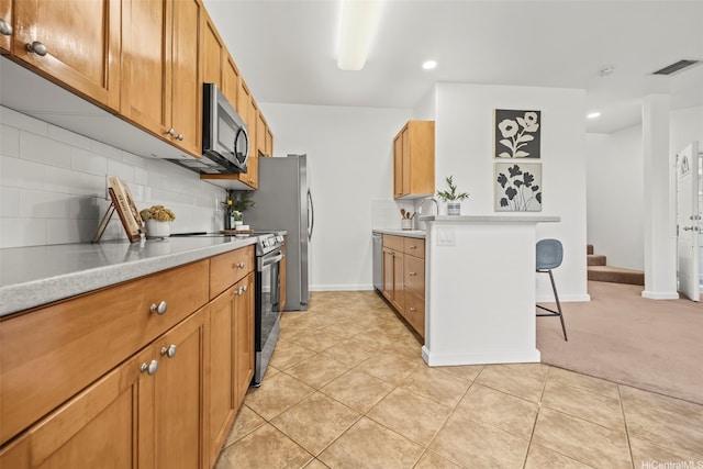 91-3082 Makalea Loop Unit 41, Ewa Beach, HI 96706 - kitchen with appliances with stainless steel finishes, a kitchen bar, light countertops, tasteful backsplash, and brown cabinetry