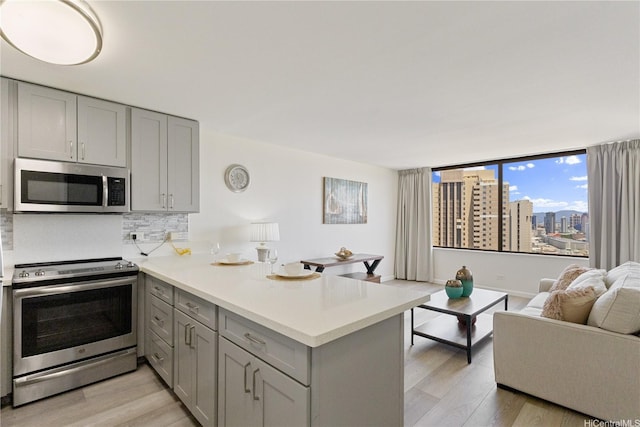 411 Hobron Ln Unit 3402, Honolulu, HI 96815 - kitchen featuring appliances with stainless steel finishes, gray cabinets, a peninsula, and light wood-style floors