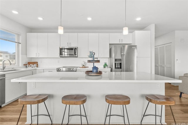 91-3575 Iwikuamoo St Unit 501, Ewa Beach, HI 96706 - kitchen with stainless steel appliances, a kitchen bar, light wood-style floors, a kitchen island, and tasteful backsplash