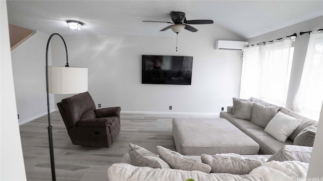 91-950 Laaulu St Unit 42E, Ewa Beach, HI 96706 - living area with a wall mounted air conditioner, ceiling fan, vaulted ceiling, light wood finished floors, and a textured ceiling