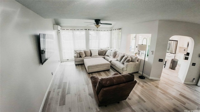 91-950 Laaulu St Unit 42E, Ewa Beach, HI 96706 - living room with arched walkways, ceiling fan, light wood-style floors, a textured ceiling, and a wall mounted air conditioner