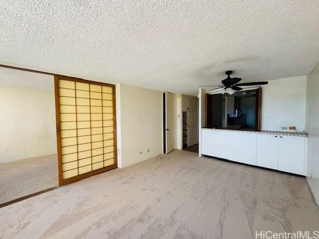 1676 Ala Moana Blvd Unit 1007, Honolulu, HI 96815 - unfurnished living room with a ceiling fan, a textured ceiling, and carpet flooring