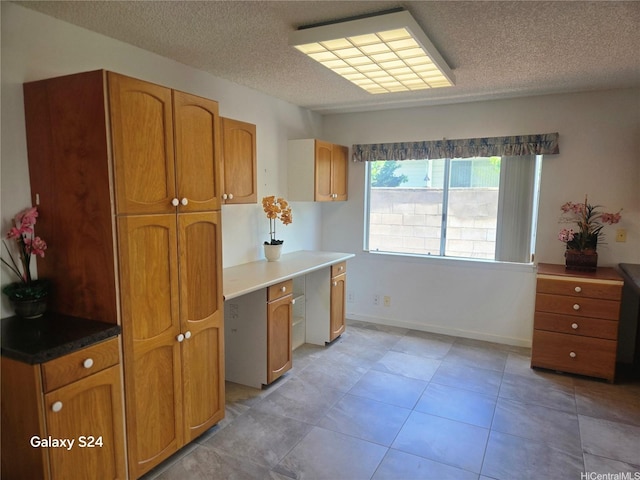 94-1060 Lelehu St, Waipahu, HI 96797 - kitchen with a textured ceiling, brown cabinetry, and light tile patterned floors