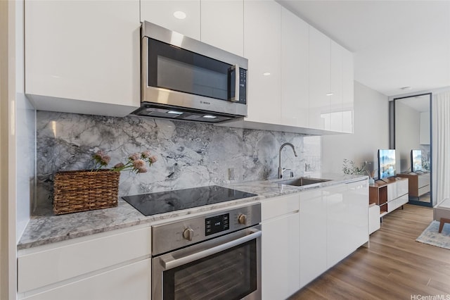 987 Queen St Unit 3209, Honolulu, HI 96814 - kitchen with appliances with stainless steel finishes, modern cabinets, white cabinets, light stone counters, and wood finished floors
