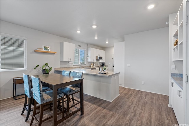 91-1725 Kapeku Loop, Ewa Beach, HI 96706 - kitchen featuring open shelves, wood finished floors, white cabinetry, stainless steel microwave, and a peninsula