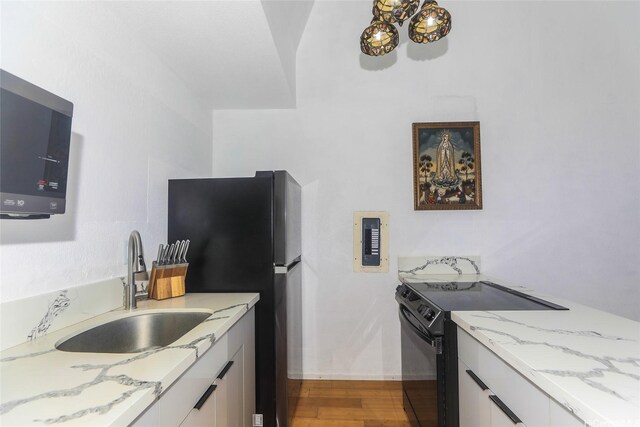 84-718 Ala Mahiku St Unit 21/97C, Waianae, HI 96792 - kitchen with black electric range, light wood-style floors, freestanding refrigerator, light stone counters, and a chandelier