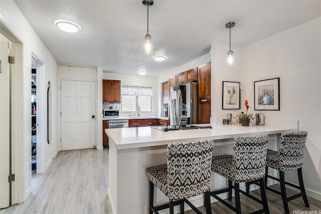 91-630 Kilaha St Unit 1, Ewa Beach, HI 96706 - kitchen with stainless steel fridge, a peninsula, a breakfast bar, light wood-style floors, and light countertops