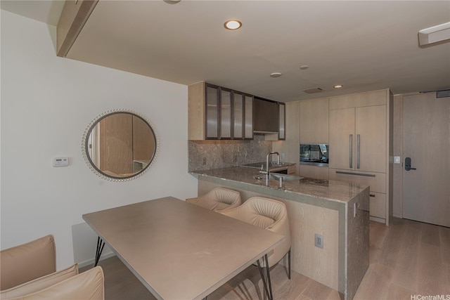 1000 Auahi St Unit 2007, Honolulu, HI 96814 - kitchen featuring light wood finished floors, a peninsula, a kitchen bar, black microwave, and recessed lighting