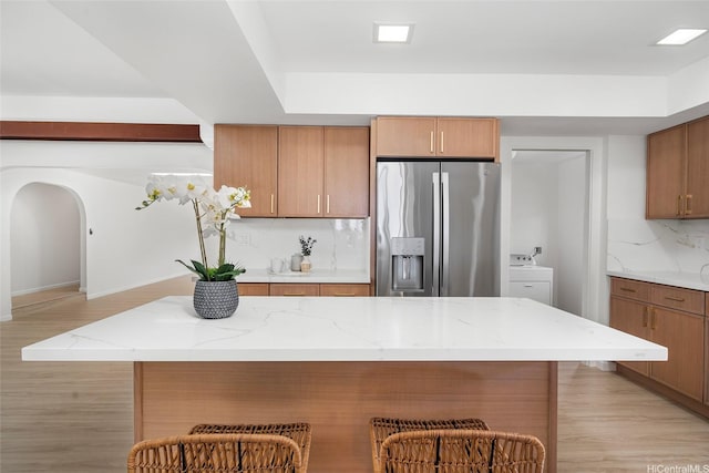 98-653 Papalealii St, Aiea, HI 96701 - kitchen featuring stainless steel fridge, decorative backsplash, light wood-style floors, a breakfast bar area, and light stone countertops