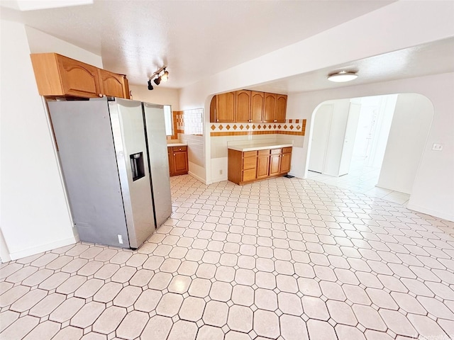 91-1206 Hanaloa St, Ewa Beach, HI 96706 - kitchen with fridge with ice dispenser, arched walkways, light countertops, backsplash, and light flooring