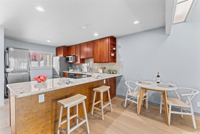 44-130-5 Mui Pl Unit 2605, Kaneohe, HI 96744 - kitchen with appliances with stainless steel finishes, light stone countertops, a peninsula, open shelves, and a breakfast bar area
