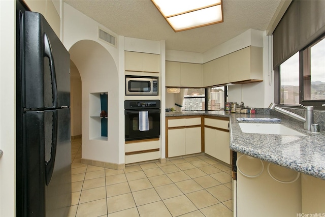 1221 Victoria St Unit 2301, Honolulu, HI 96814 - kitchen with black appliances, cream cabinets, light tile patterned floors, light stone counters, and a textured ceiling