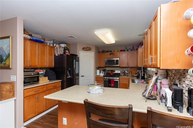 91-1268 Kilipue St, Ewa Beach, HI 96706 - kitchen with appliances with stainless steel finishes, light countertops, a peninsula, backsplash, and dark wood finished floors