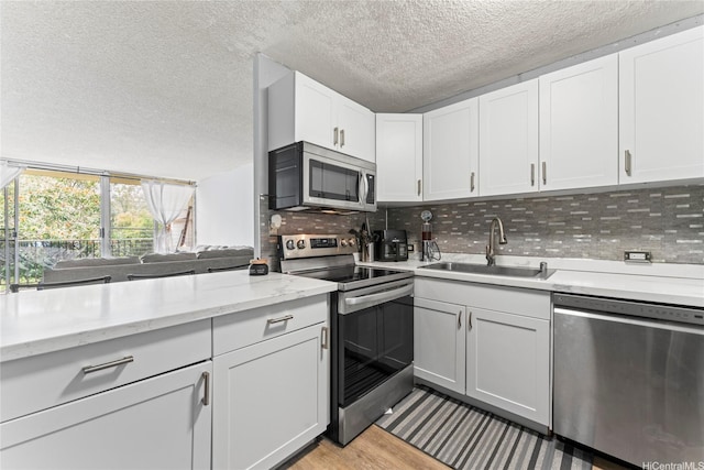 95-2035 Waikalani Pl Unit B303, Mililani, HI 96789 - kitchen with stainless steel appliances, a textured ceiling, backsplash, white cabinets, and light wood-style flooring