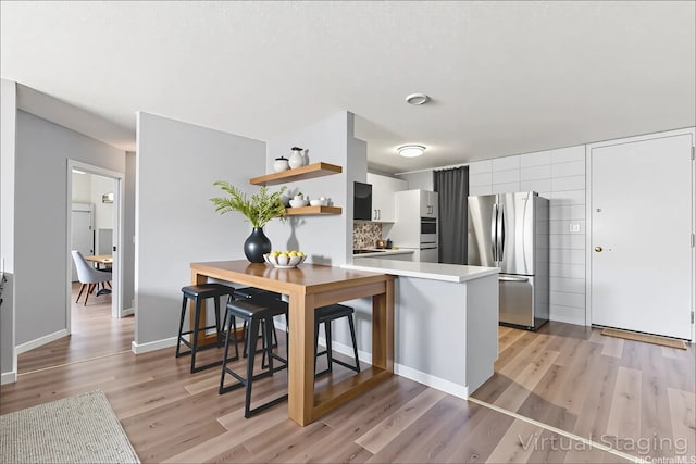 95-2035 Waikalani Pl Unit B303, Mililani, HI 96789 - kitchen featuring freestanding refrigerator, open shelves, light countertops, light wood-style floors, and a peninsula