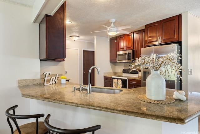 55-439 Naniloa Loop, Laie, HI 96762 - kitchen with appliances with stainless steel finishes, a textured ceiling, ceiling fan, a kitchen bar, and a peninsula