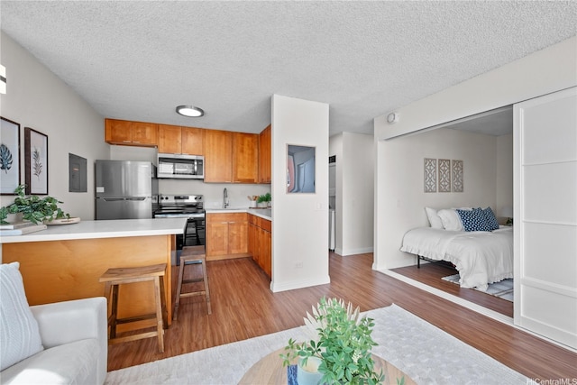 2754 Kuilei St Unit 1601, Honolulu, HI 96826 - kitchen featuring appliances with stainless steel finishes, open floor plan, light wood-style flooring, light countertops, and a textured ceiling