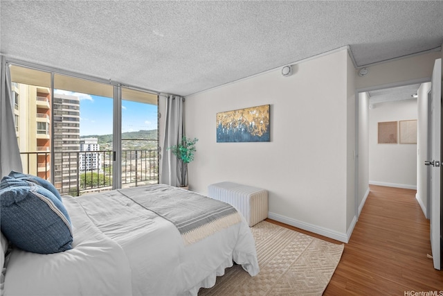 2754 Kuilei St Unit 1601, Honolulu, HI 96826 - bedroom with access to outside, wood finished floors, a textured ceiling, a wall of windows, and radiator