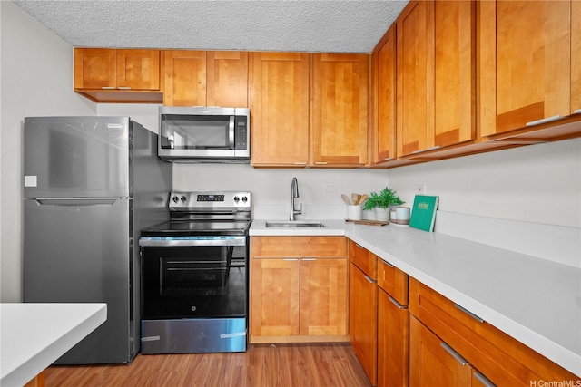 2754 Kuilei St Unit 1601, Honolulu, HI 96826 - kitchen with appliances with stainless steel finishes, light countertops, light wood-style floors, a textured ceiling, and brown cabinets
