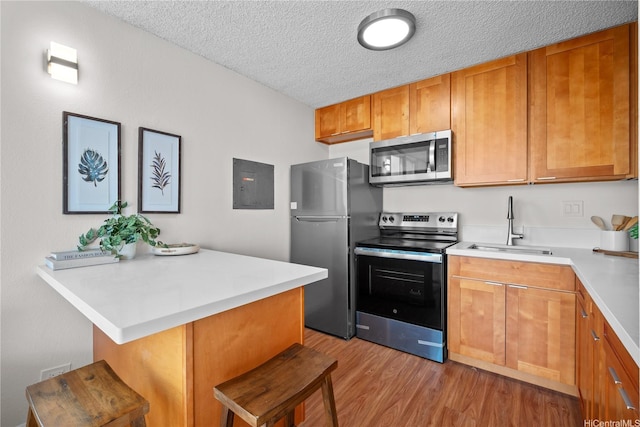 2754 Kuilei St Unit 1601, Honolulu, HI 96826 - kitchen with appliances with stainless steel finishes, a kitchen bar, a textured ceiling, light countertops, and light wood finished floors