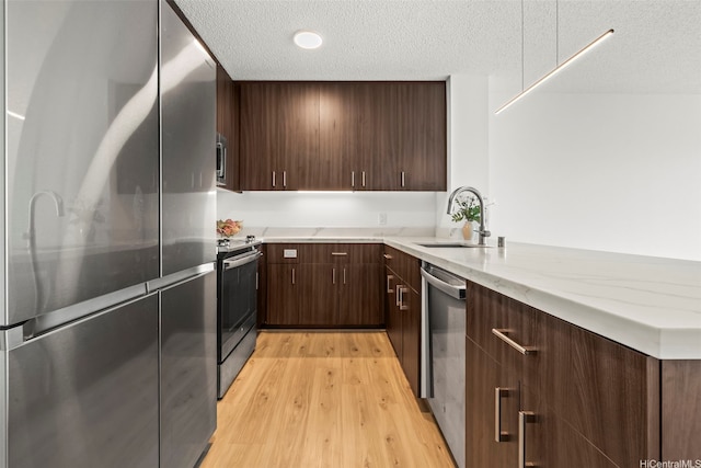 615 Keawe St Unit 3005, Honolulu, HI 96813 - kitchen featuring appliances with stainless steel finishes, a textured ceiling, light wood-style floors, dark brown cabinets, and light stone countertops
